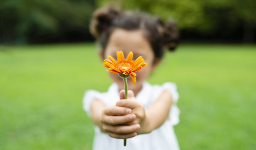 Bambina con un fiore a primavera