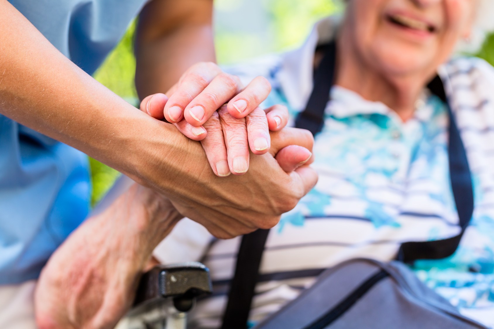 nurse consoling senior woman holding her hand