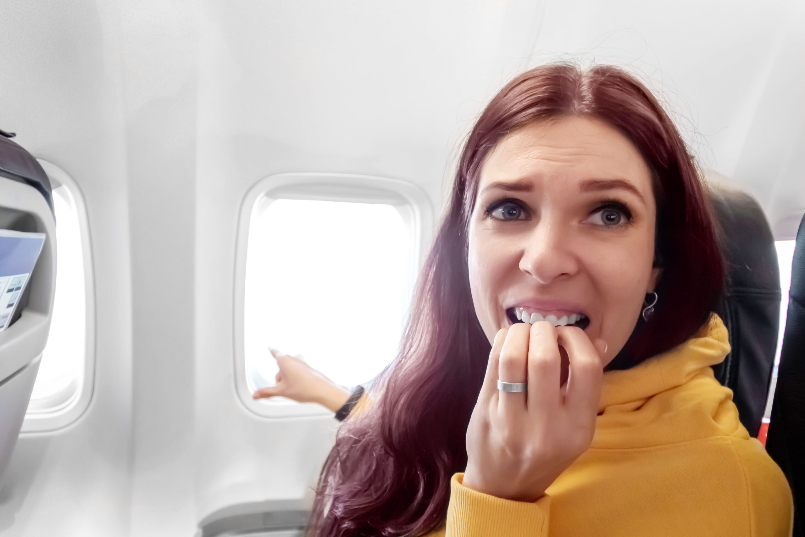 the girl is afraid to fly on the plane. rinsing, bites fingers. concept of travel, flight, fear.